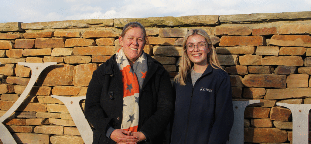 Freya Askew and Anna Warnecke, CEO of Kynren photographed outside in front of a stone 'Kynren' sign.