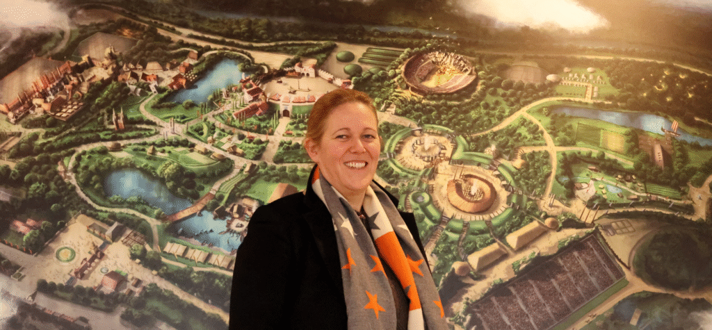 Anna Warnecke, CEO of Kynren, photographed in front of a map of Kynren - The Storied Lands, set to open Summer 2026.