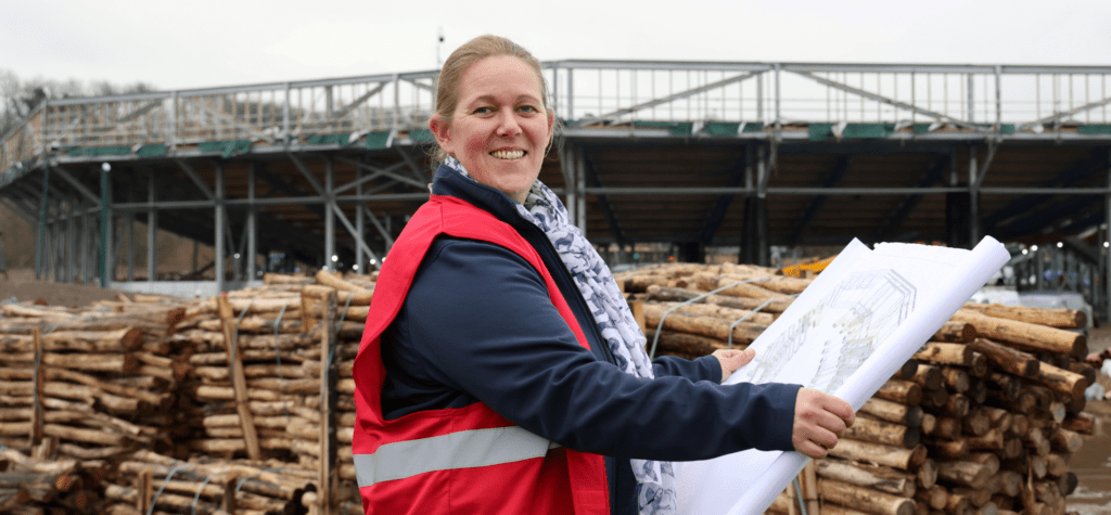 Anna Warnecke with building plans in front of the building site of The Lost Feather