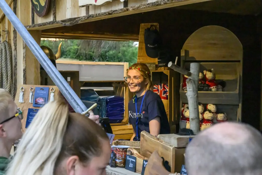 A girl looks out from behind a shop till.