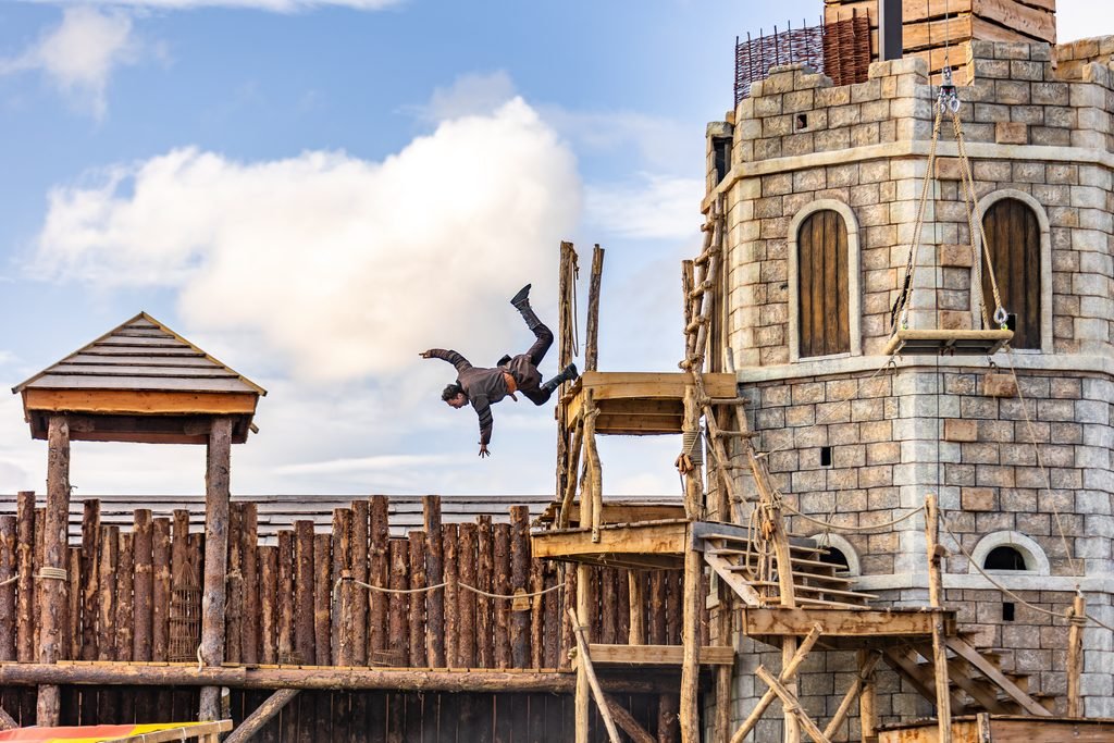 a man dives from an intricately designed tower set for Legend of the Wear, one of the shows in Kynren - The Storied Lands