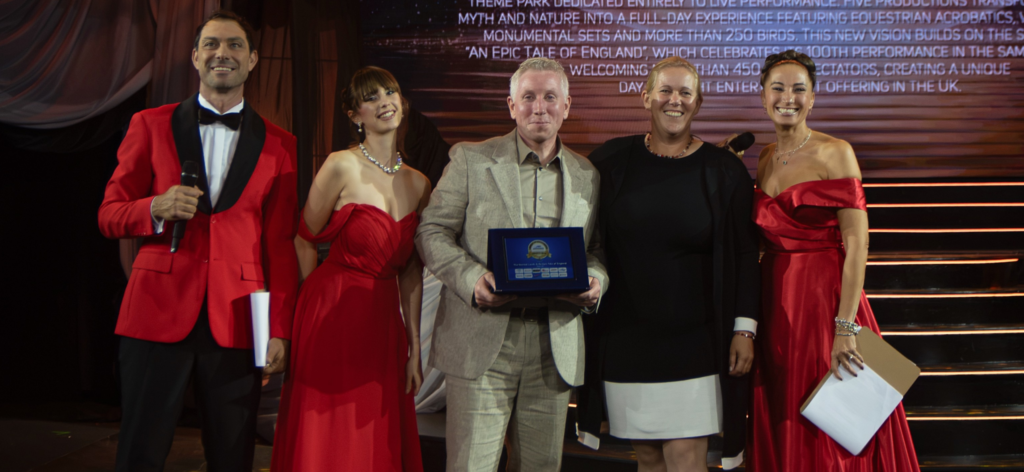 Five people smile for the camera at an awards ceremony, one in the centre holds an award certificate.